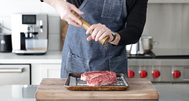 adding pepper to steaks