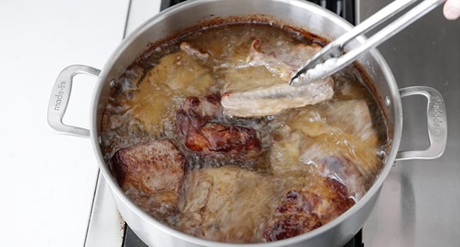 adding ribs to a pot of lard and cooked pork