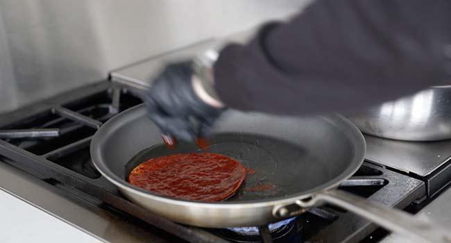 cooking an enchilada sauce dipped tortilla