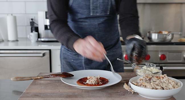 adding chicken to a fried enchilada