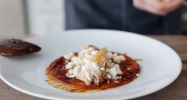 cheese, chicken, and onions on an enchilada tortilla