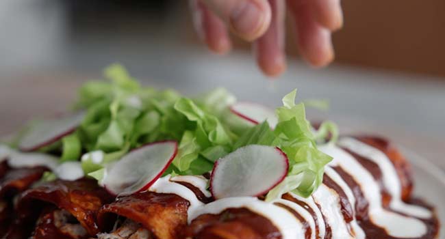 garnishing an enchilada with radishes