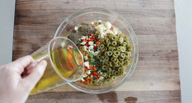 adding oil to a bowl of vegetables