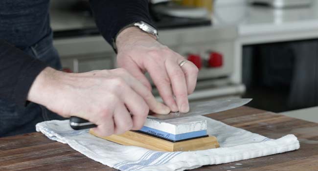 scraping a knife on a polishing stone