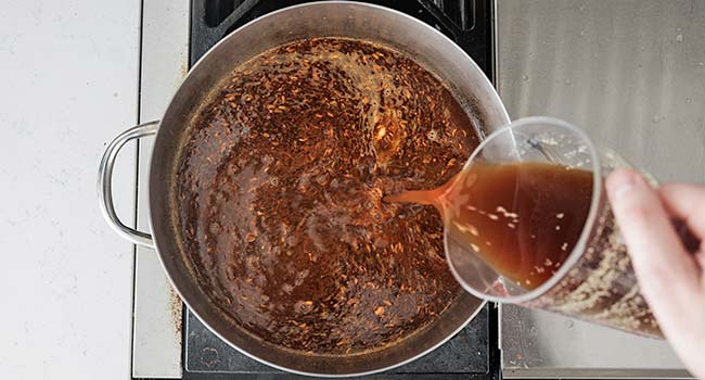 adding broth to a pot