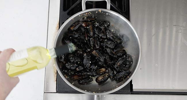 adding wine to cooked mussels