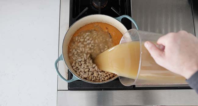 adding chicken stock to beans