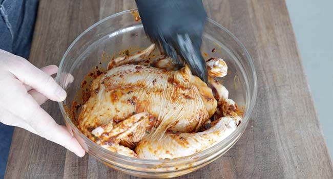 rubbing a chicken with marinade