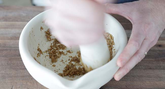 grinding seeds with garlic and ginger in a mortar