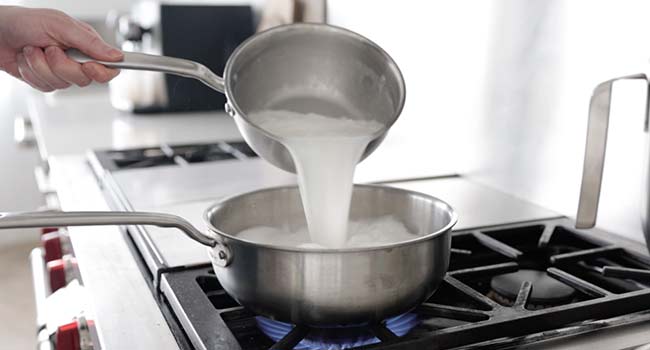 adding milk to a pot of rice