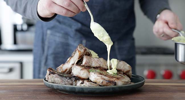 adding mustard sauce to pork chops