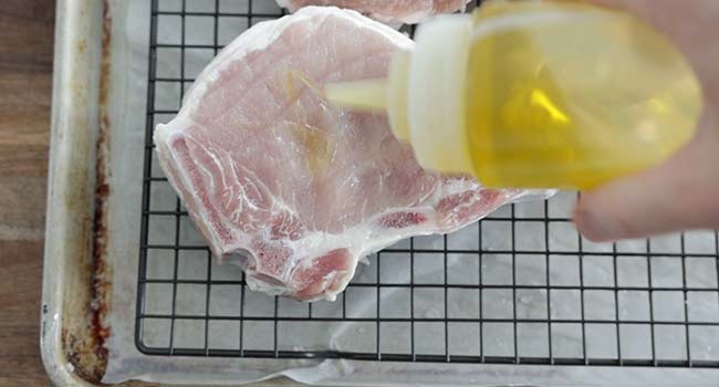 adding oil to pork chops