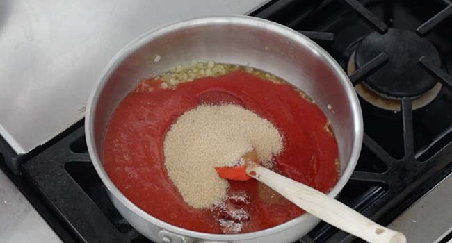 adding spices and brown sugar to a pot of tomato puree