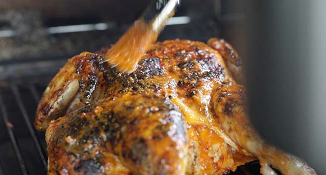 basting a peri peri chicken on the grill