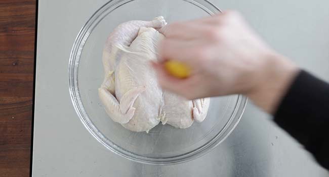 adding lemon juice to a chicken