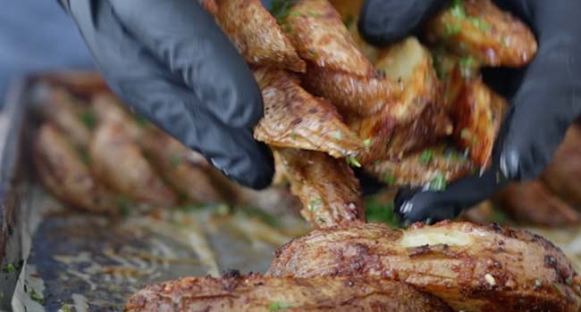 tossing potato wedges with parsley