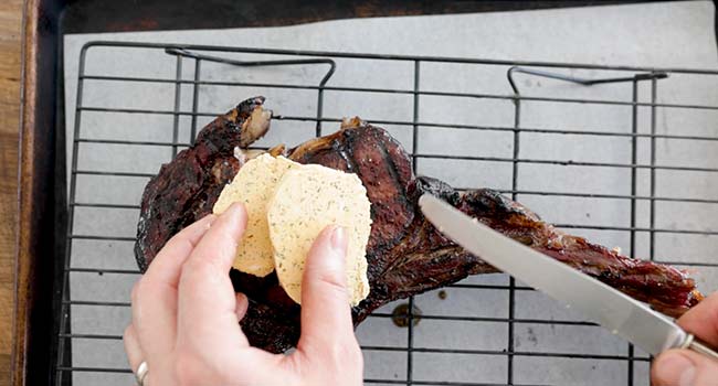 adding butter onto cooked steaks