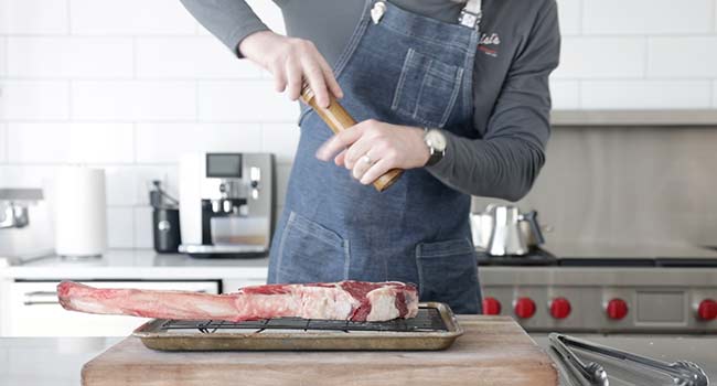 adding pepper to a steak