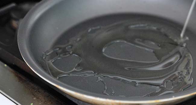 adding oil to a saute pan