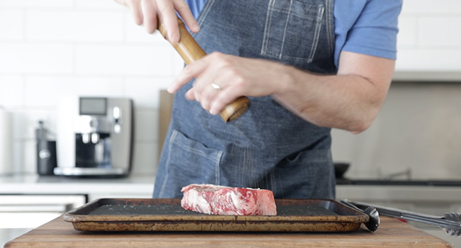 seasoning a steak with pepper