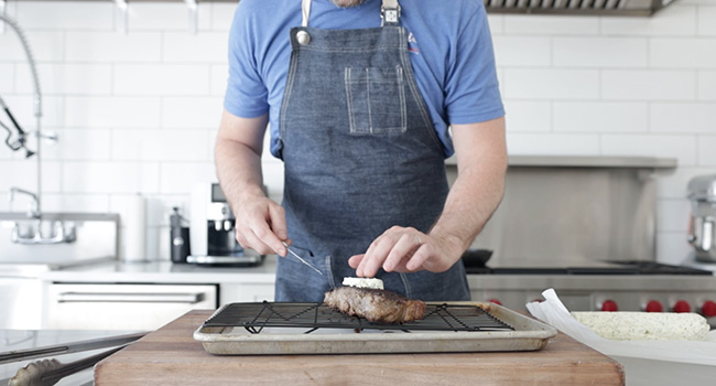 adding herb butter to steak