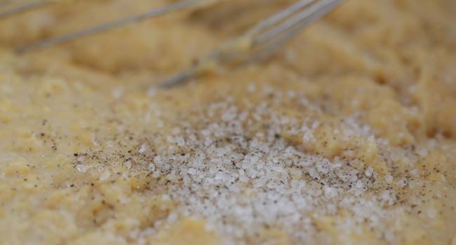 stiring salt and pepper into creamy polenta