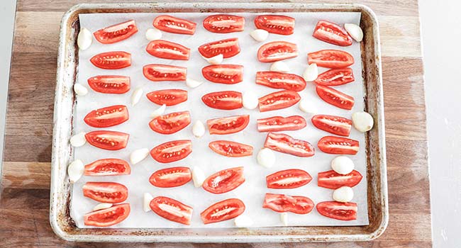 tomatoes on a sheet tray with garlic