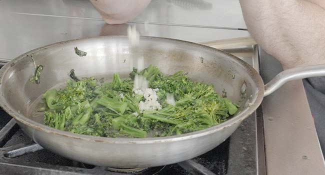 adding garlic to broccolini