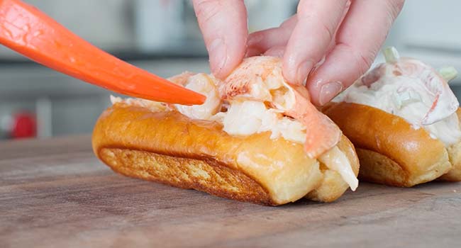 adding lobster to a roll