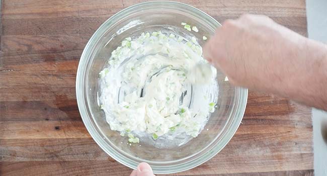 mixing mayo with celery in a bowl