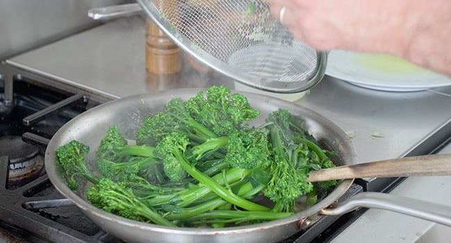 adding broccolini to a pan