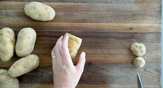 slicing the ends off of potatoes