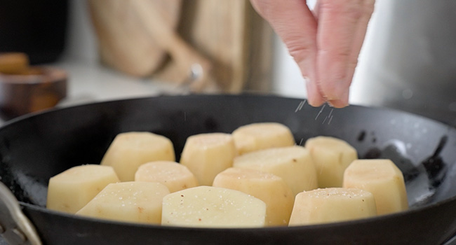 seasoning potatoes in a pan