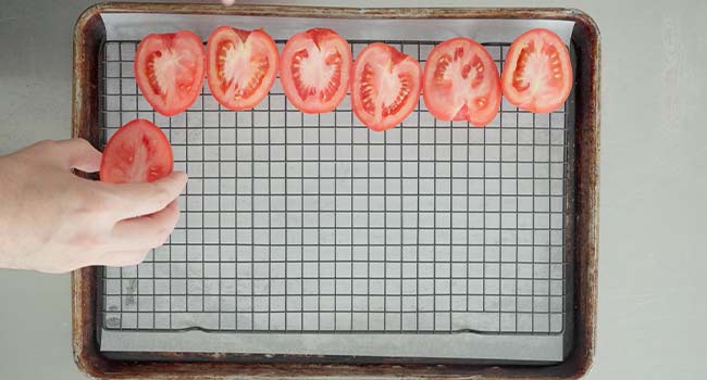 adding slices tomtatoes to a rack