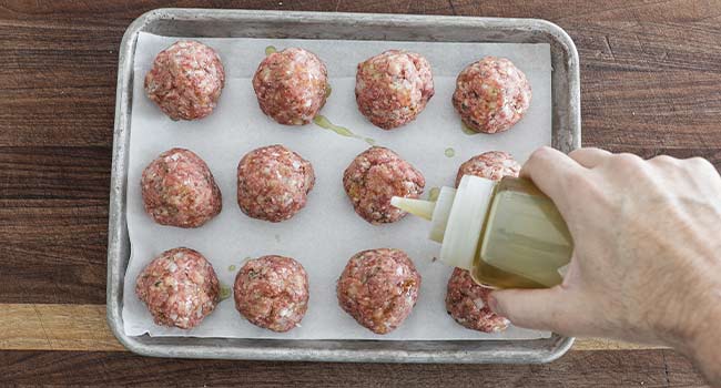 adding olive oil to meatballs