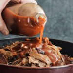 pouring bbq sauce on pulled pork