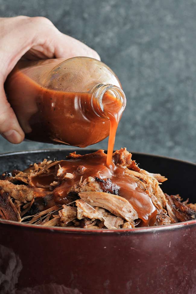 pouring bbq sauce on pulled pork