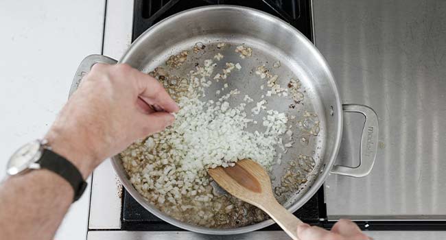 seasoning onions in a pan