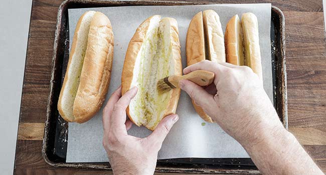 brushing hoagie buns with olive oil