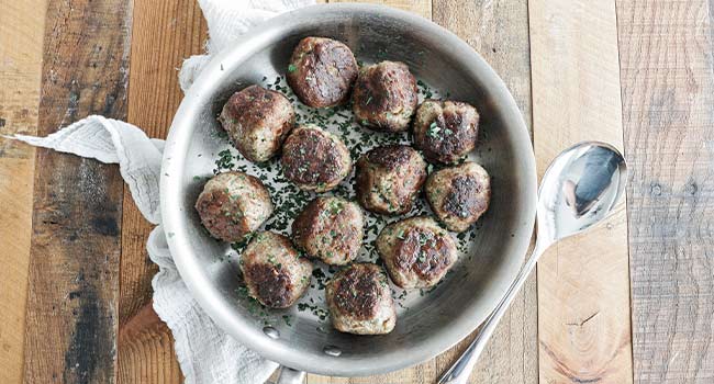 seared meatballs with herbs in a pan