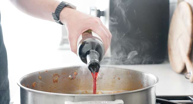 adding wine to a pot