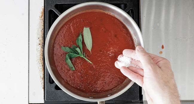 adding herbs to tomato sauce