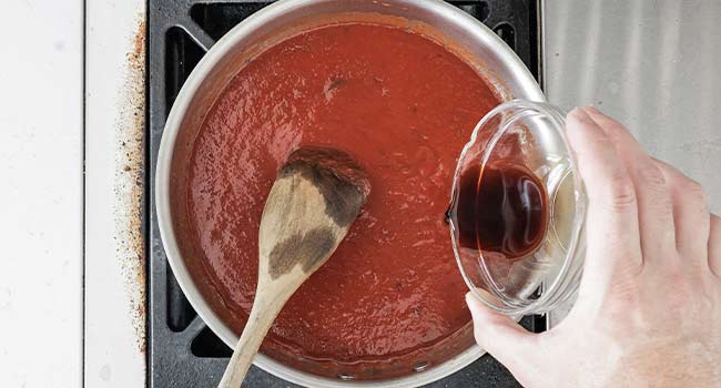 adding vinegar to tomato sauce