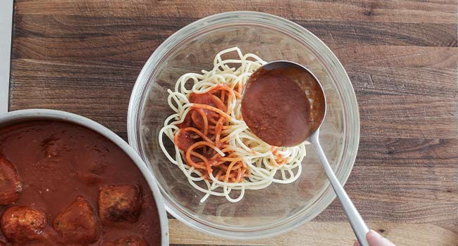 pouring sauce on spaghetti