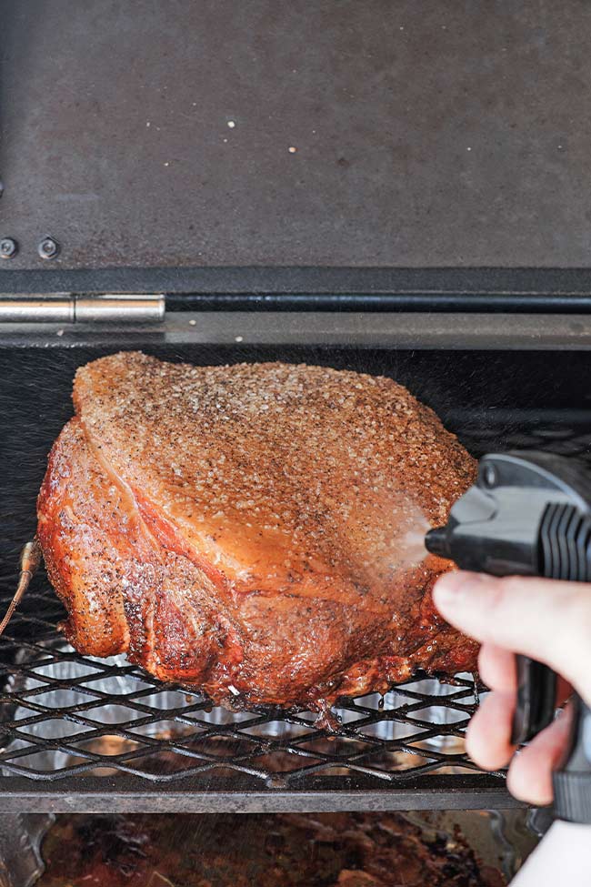 spritzing a smoked pork butt