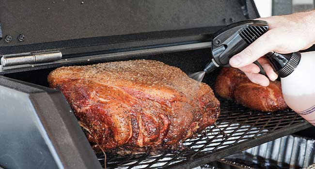 spraying meat with a bbq spritzer