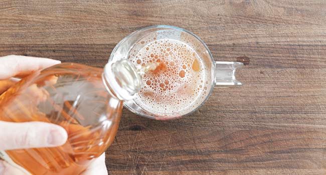 adding apple juice to a measuring cup