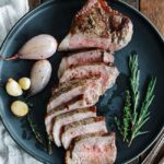 sliced steak on a plate with herbs