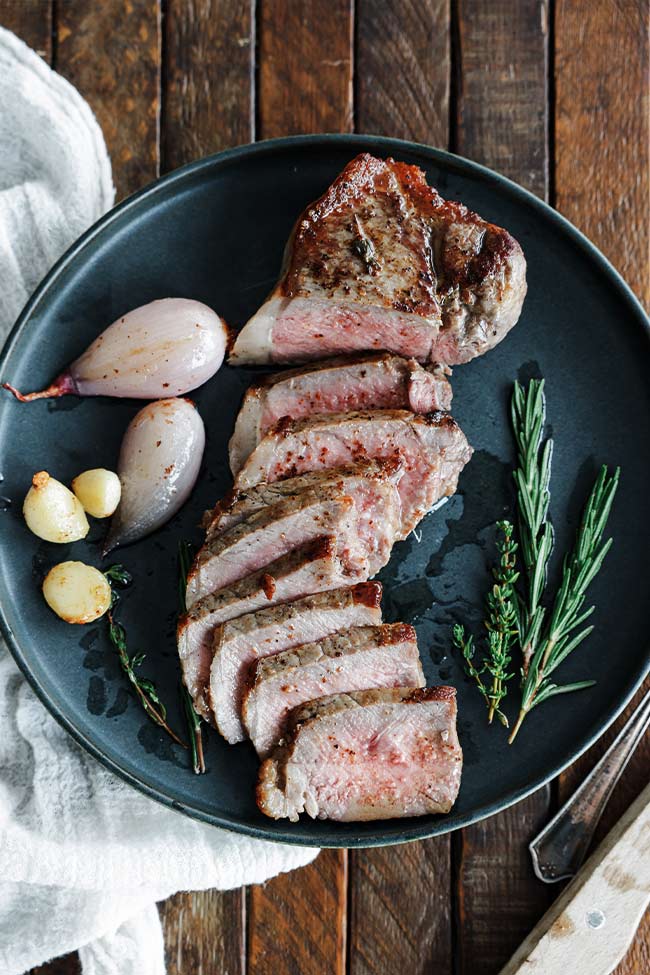 sliced steak on a plate with herbs