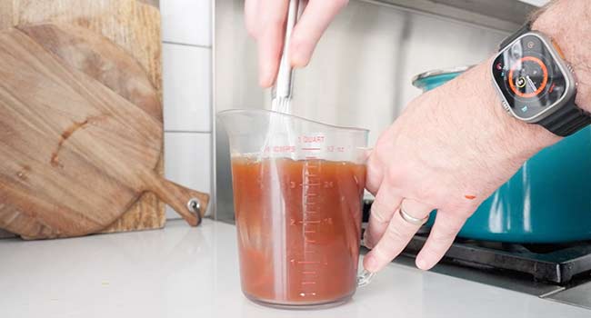 whisking tomato paste and beef stock